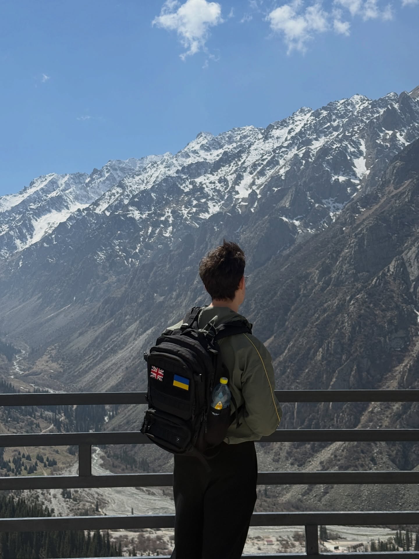 Looking out over snow-dusted mountains with a backpack bearing UK and Ukrainian flag patches