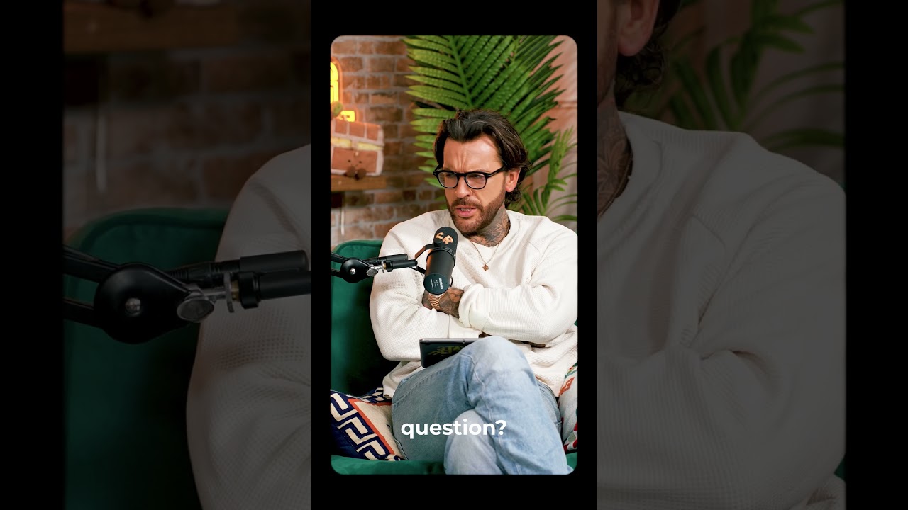 Podcast guest on a green couch leaning toward a microphone